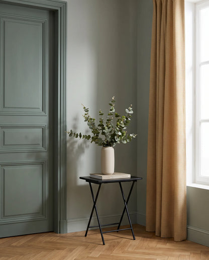 Bouquet artificiel vert gris sur une table d'appoint noire, entrée à la porte vert sauge