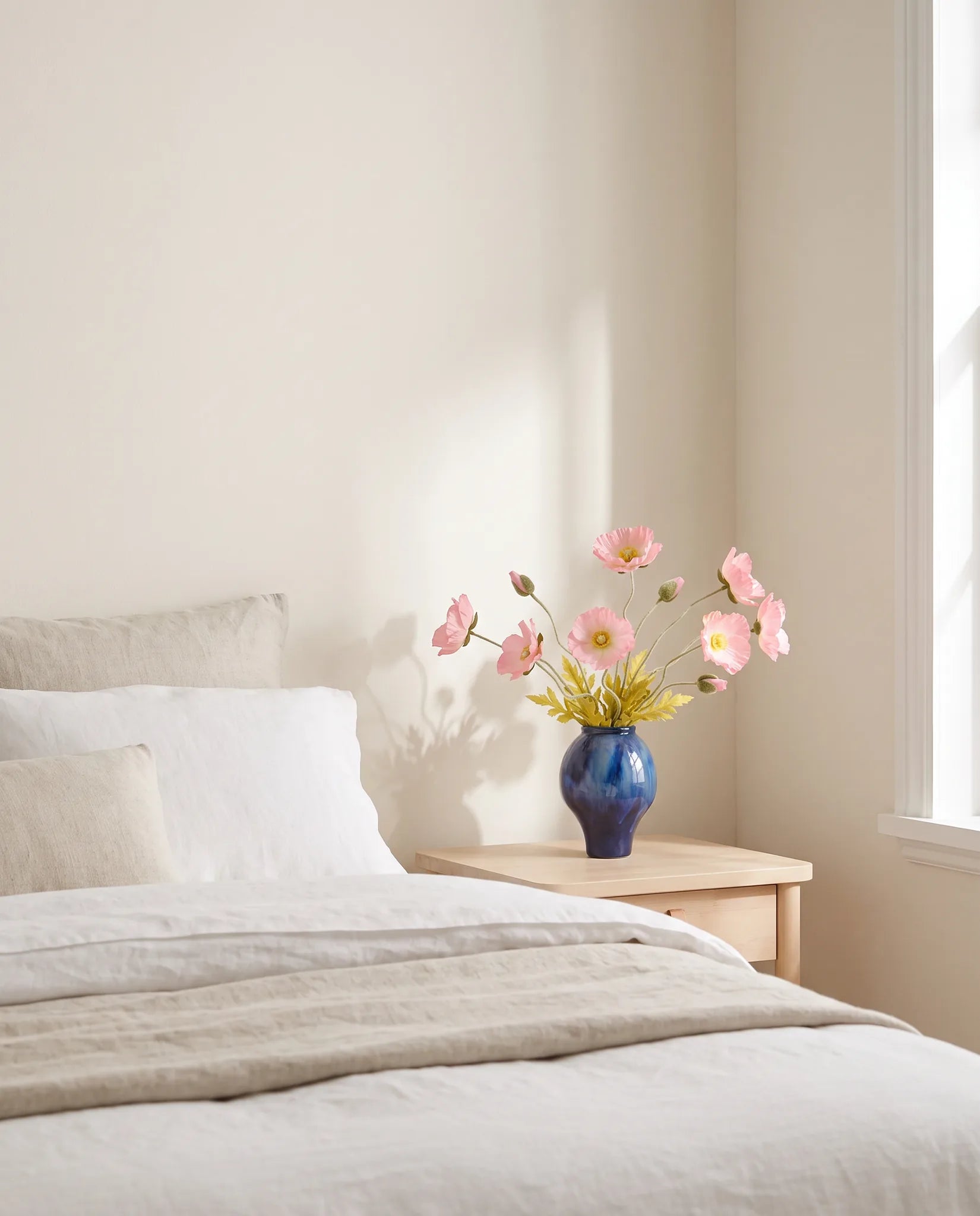 Bouquet artificiel rose dans une chambre, lumière du matin sur le linge de lit en lin