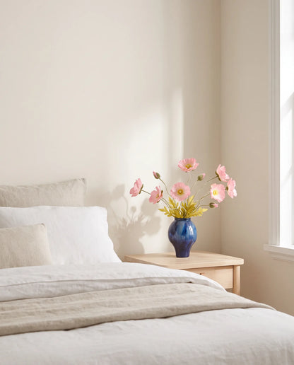 Bouquet artificiel rose dans une chambre, lumière du matin sur le linge de lit en lin