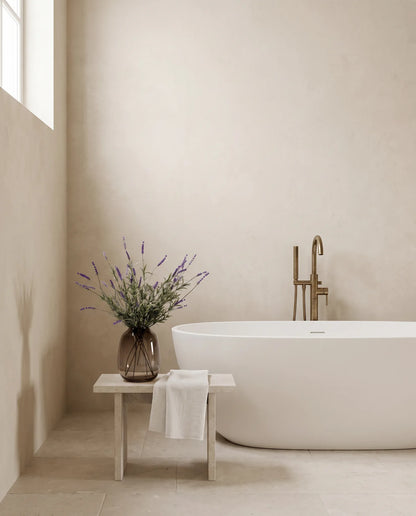 Bouquet artificiel violet sur un tabouret en pierre, salle de bain à la baignoire îlot