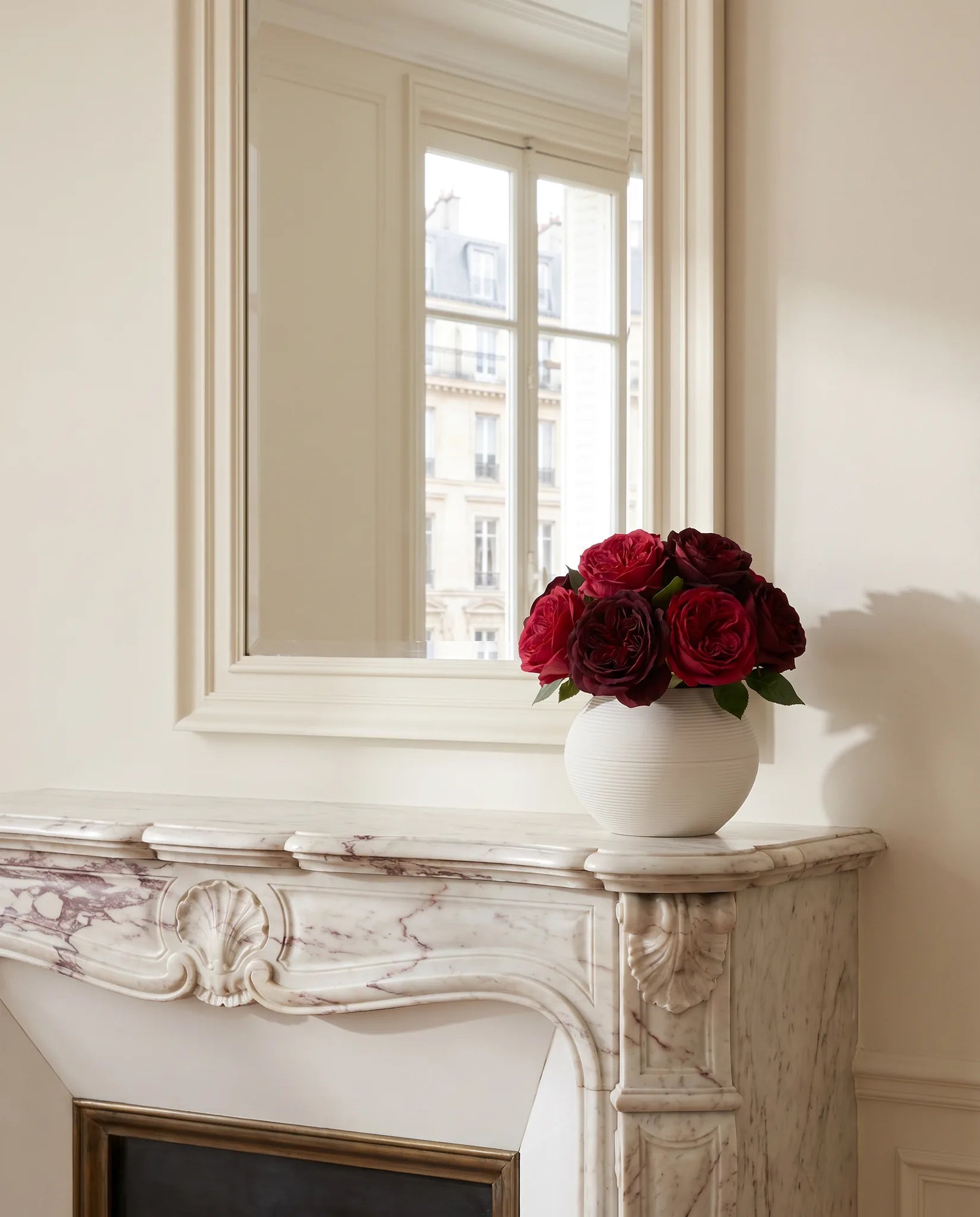 Bouquet artificiel bordeaux devant le grand miroir d'un salon parisien rénové