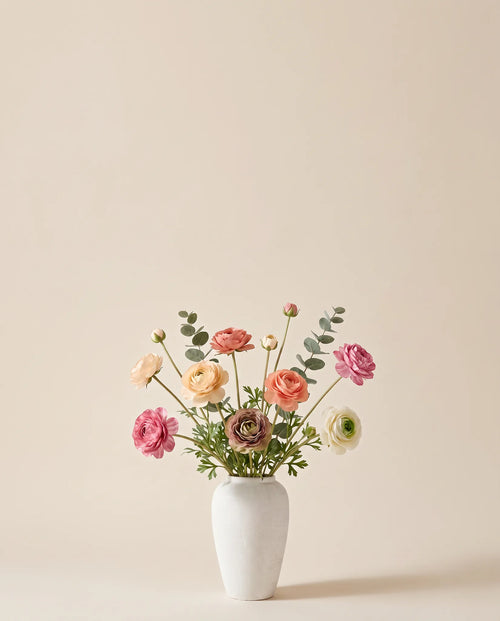 Bouquet artificiel de renoncules multicolores dans un vase en céramique
