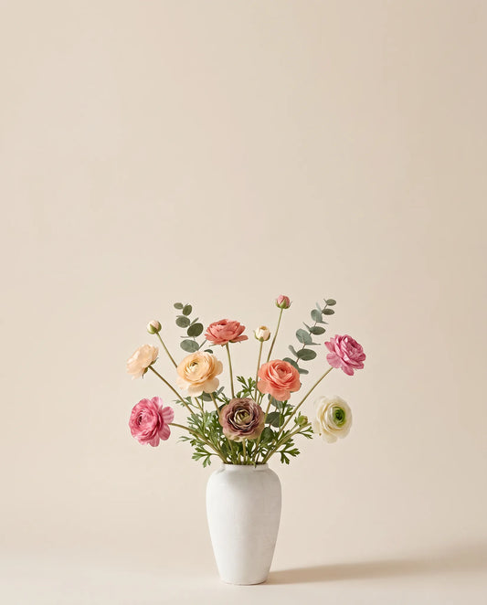 Bouquet artificiel de renoncules multicolores dans un vase en céramique