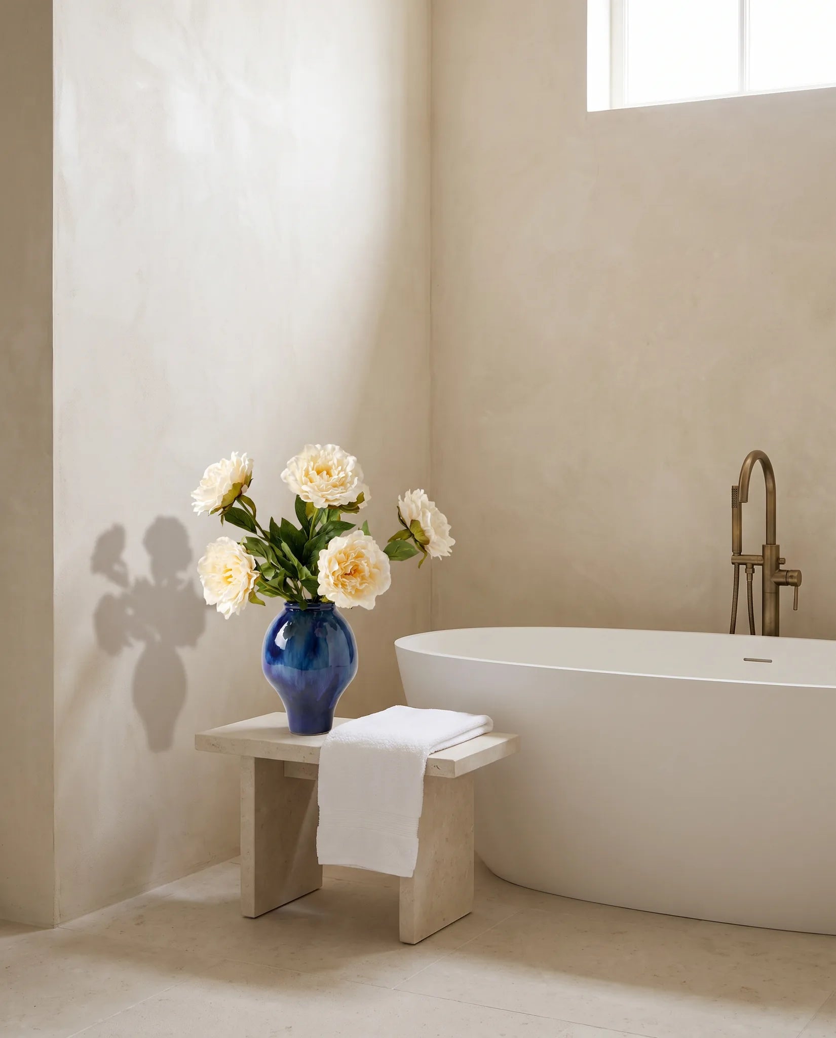 Bouquet artificiel blanc dans une salle de bain, robinetterie en laiton vieilli