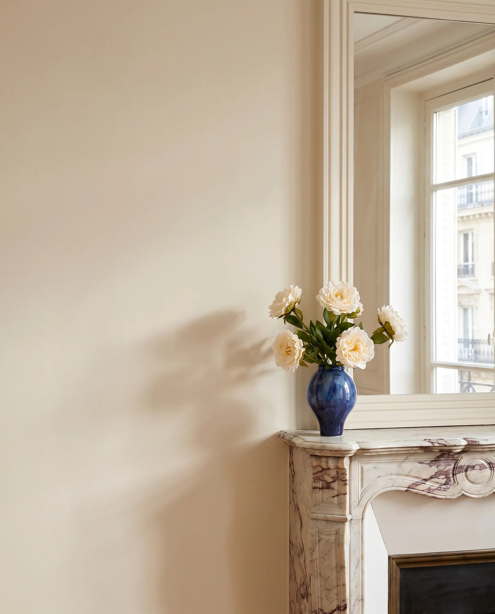 Bouquet artificiel blanc sur une cheminée en marbre, salon parisien rénové