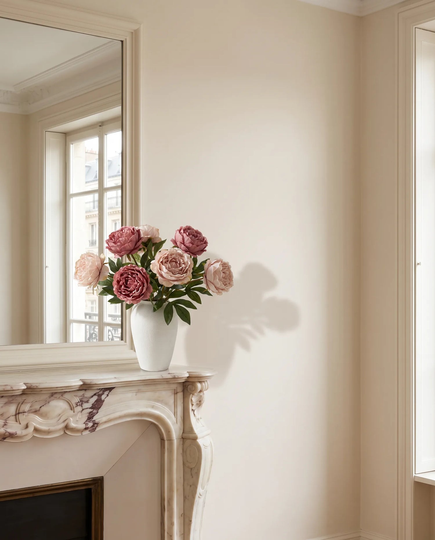 Grand bouquet artificiel rose dans un salon parisien rénové, cheminée en marbre