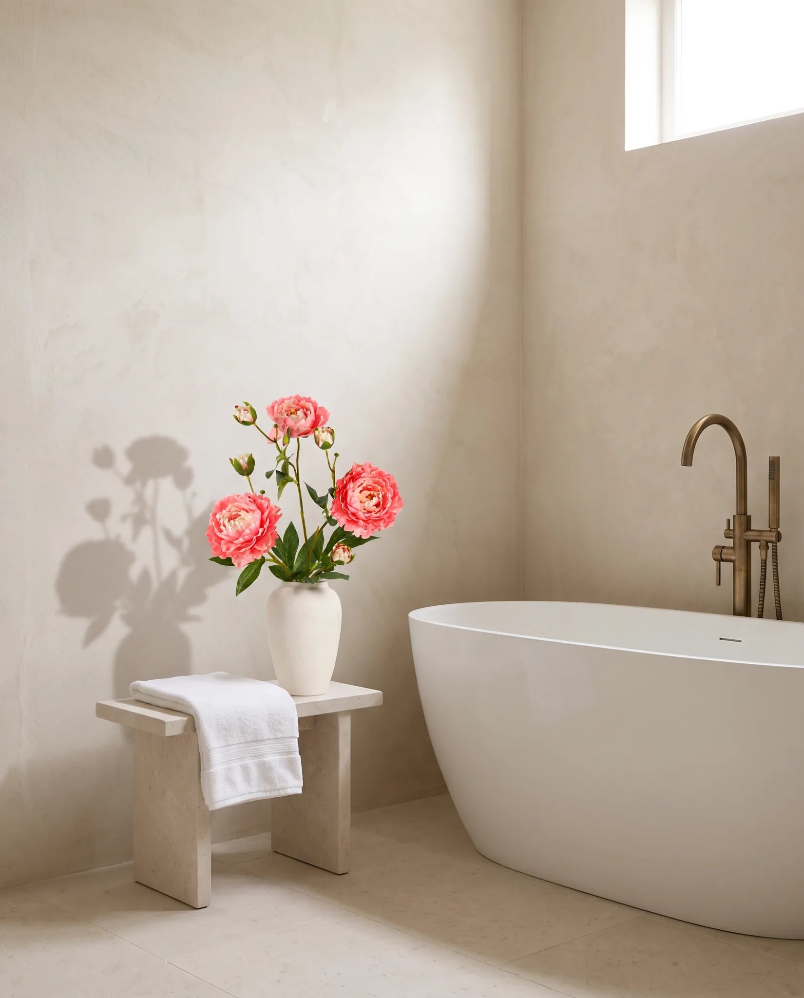 Bouquet artificiel orange pêche près d'une baignoire îlot, salle de bain en pierre