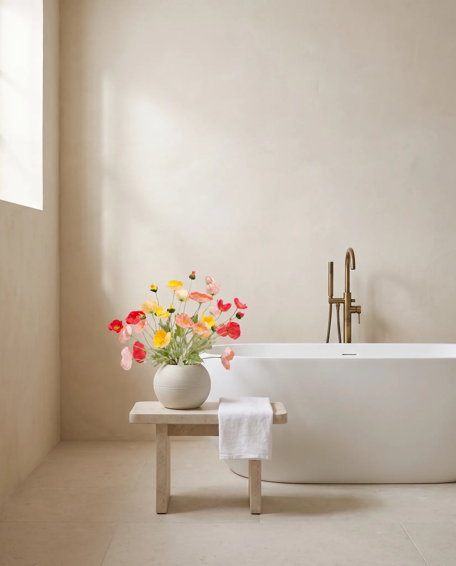 Bouquet artificiel multicolore sur un tabouret en pierre, salle de bain à la baignoire îlot
