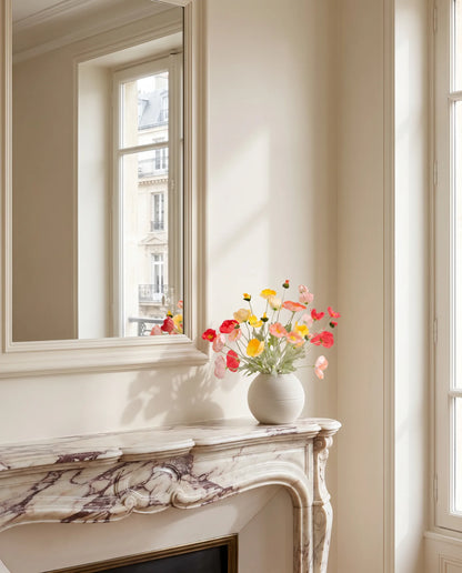 Bouquet artificiel multicolore sur une cheminée en marbre, salon parisien rénové