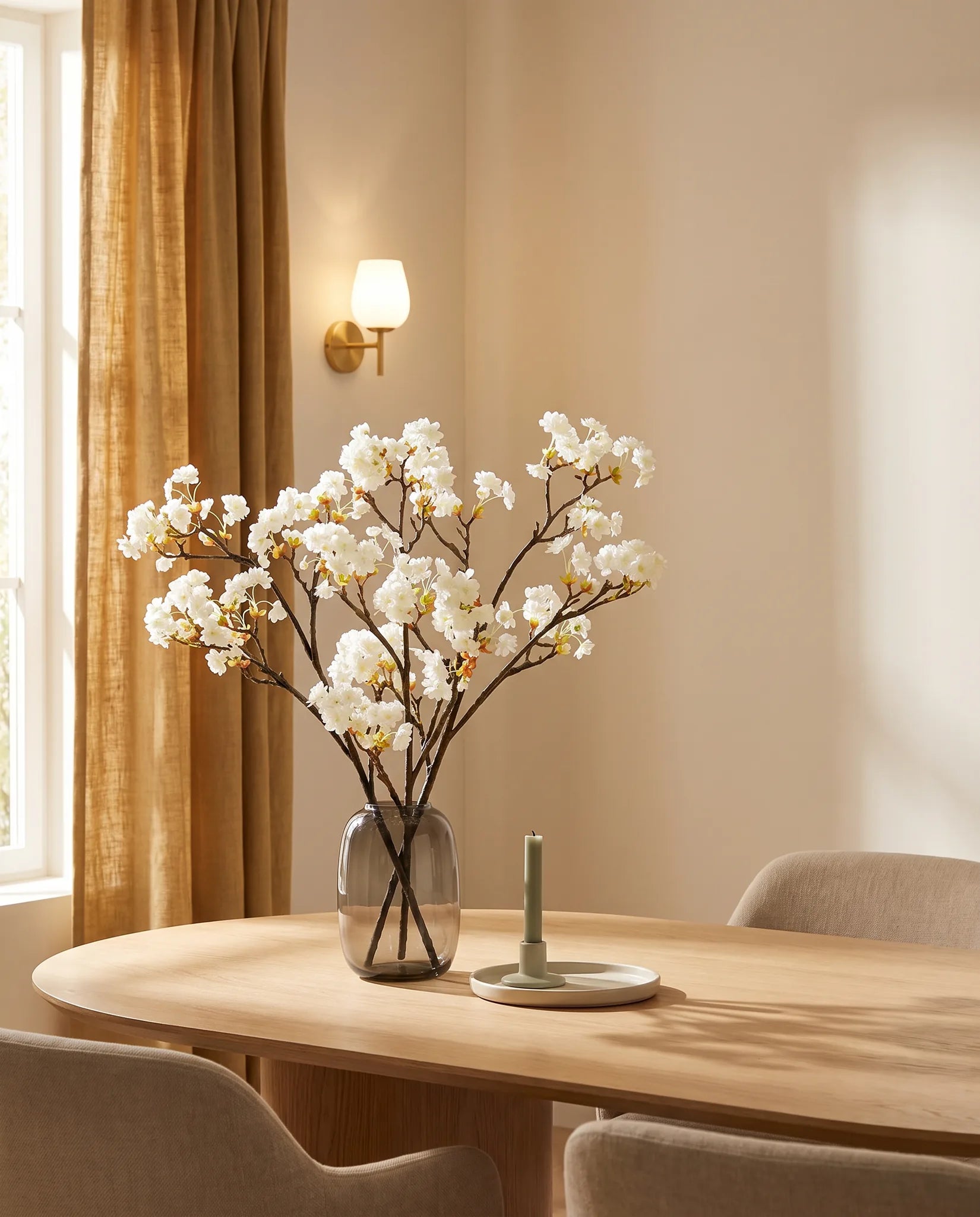 Branches artificielles blanches sur une table ovale en chêne clair, salle à manger