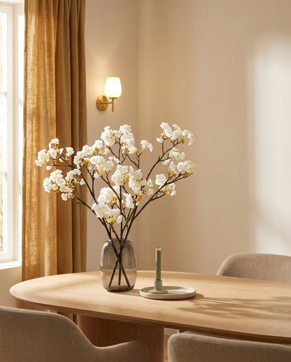 Branches artificielles blanches sur une table ovale en chêne clair, salle à manger