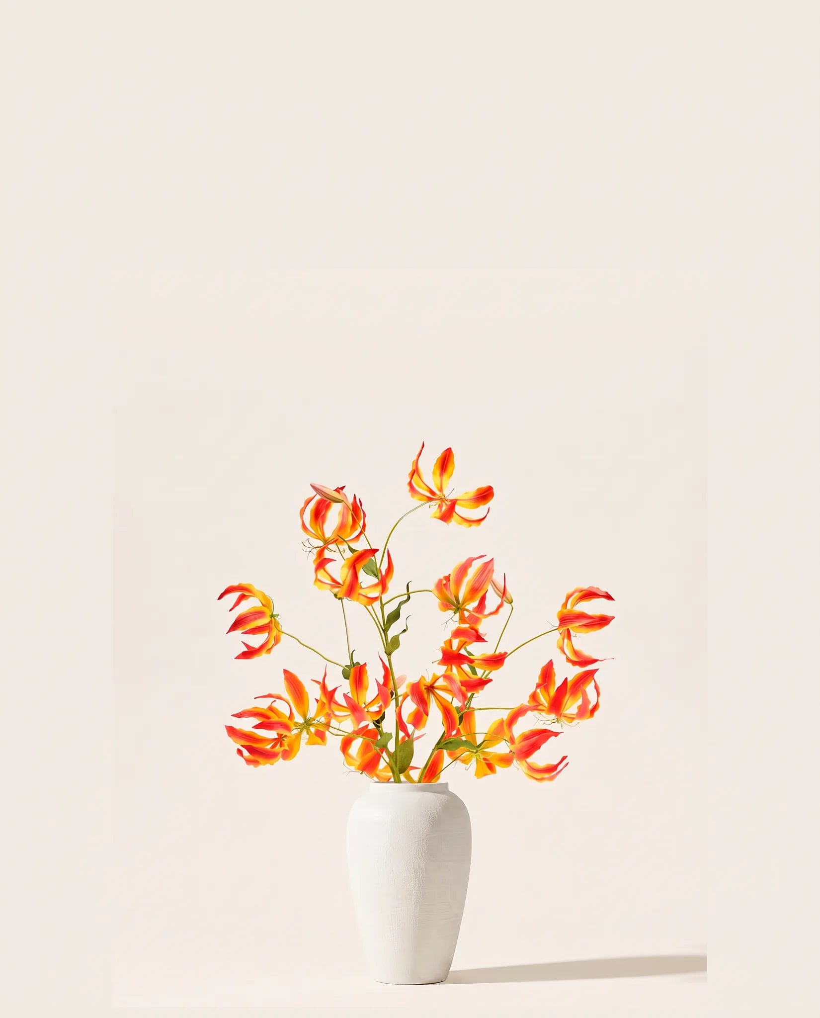 Bouquet artificiel de glorieuses rouge et or dans un vase en céramique