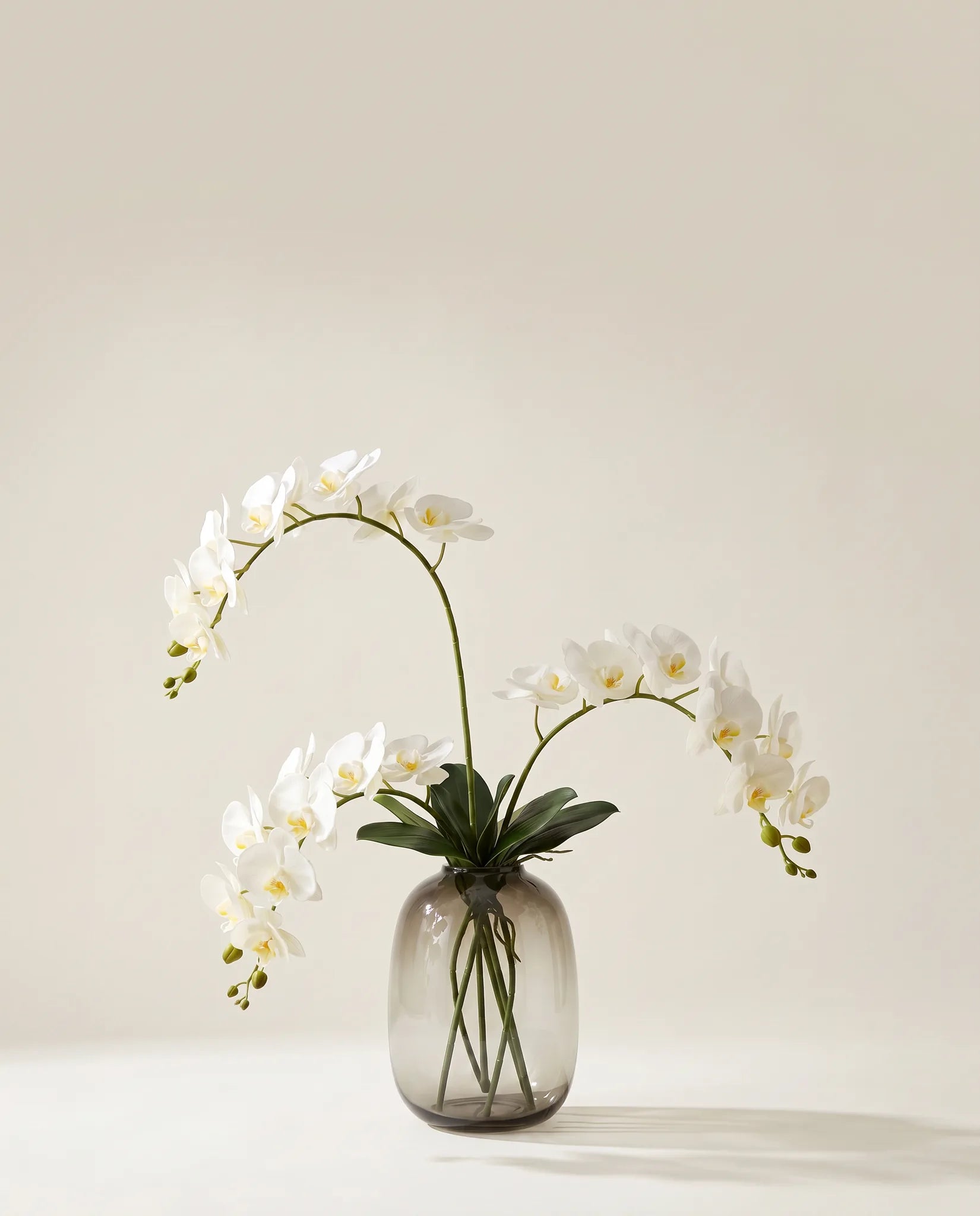 Bouquet artificiel d'orchidées blanches dans un vase en verre ambré