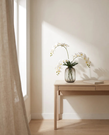 Bouquet artificiel blanc dans la lumière latérale d'un bureau, table en chêne clair