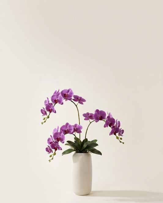 Bouquet artificiel d'orchidées violettes dans un vase en céramique