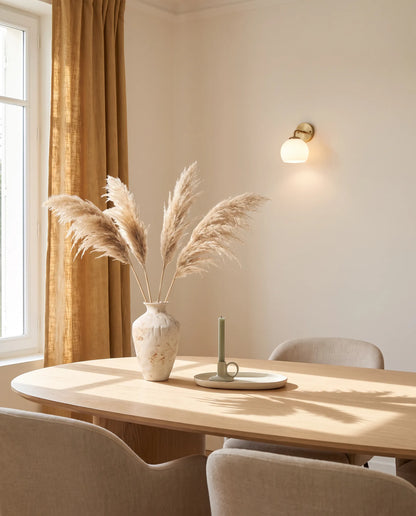 Bouquet de pampa artificielle beige près d'une table ovale en chêne clair