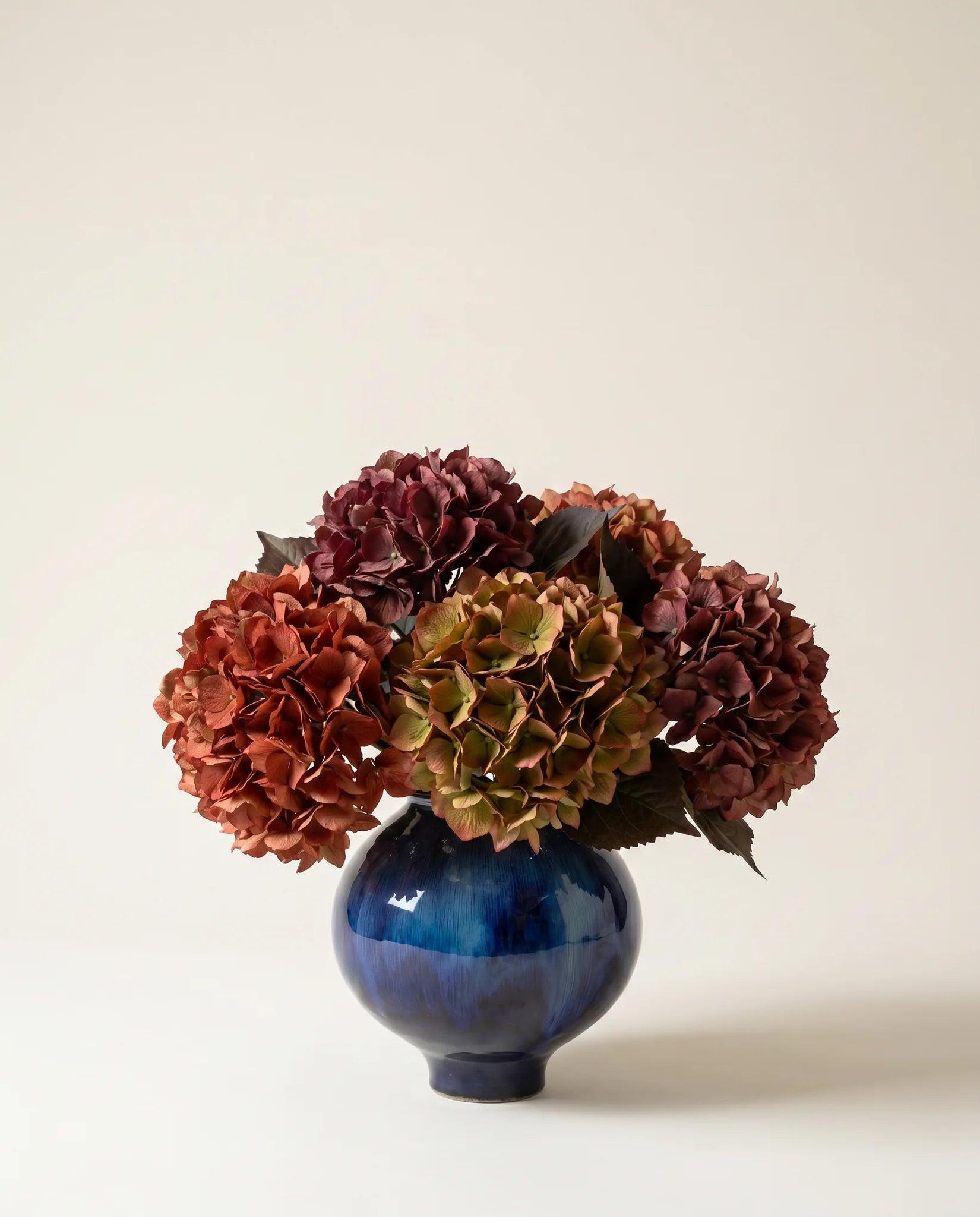 Vase céramique émaillé bleu nuit avec bouquet d'hortensias rouge automnal artificiels