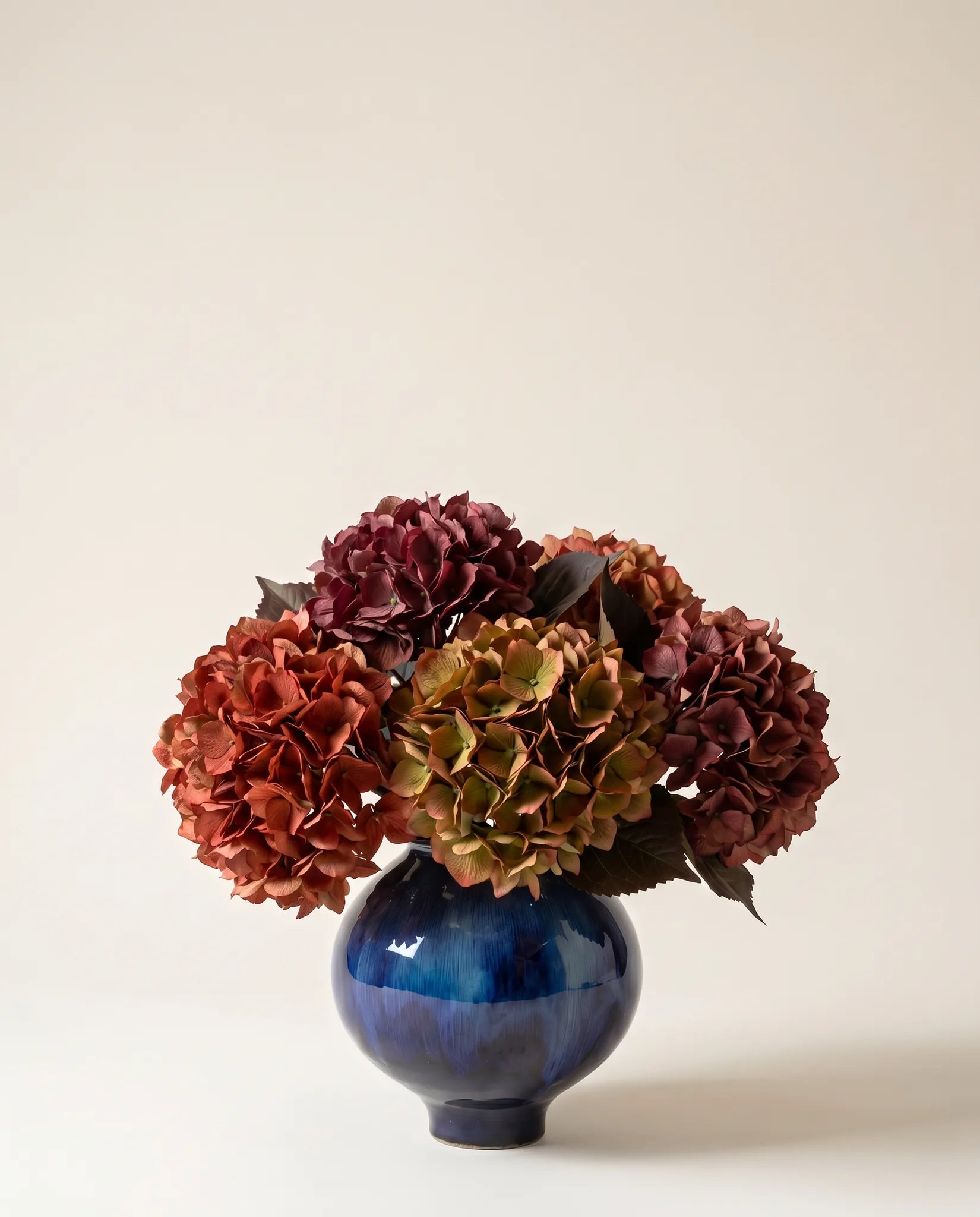 Bouquet artificiel d'hortensias rouge et bordeaux dans un vase en céramique