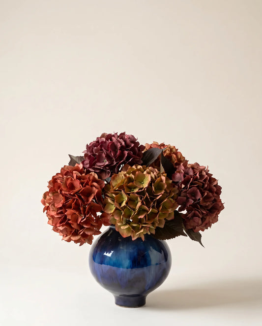 Bouquet artificiel d'hortensias rouge et bordeaux dans un vase en céramique