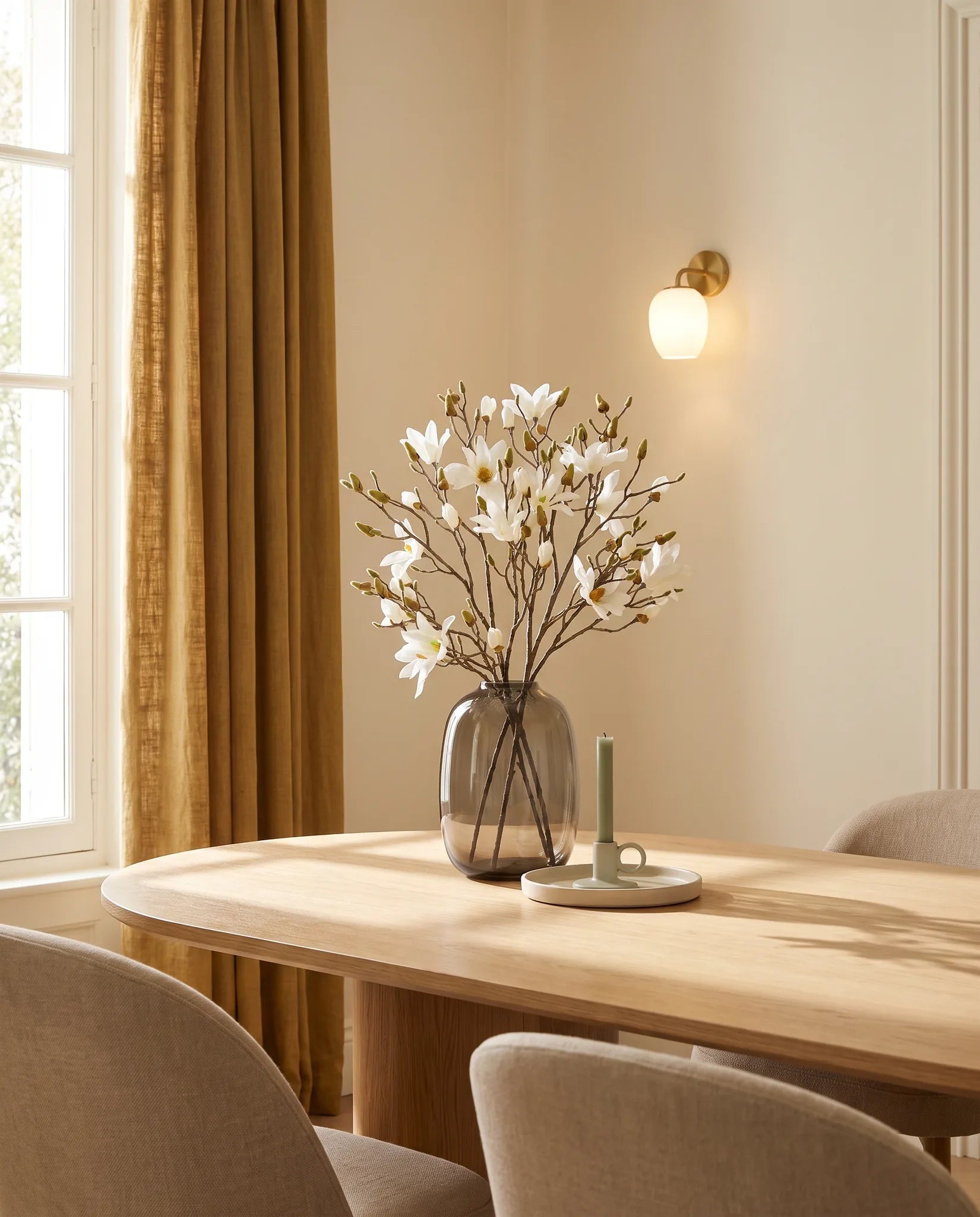 Grand bouquet artificiel crème près d'une table ovale en chêne clair, salle à manger