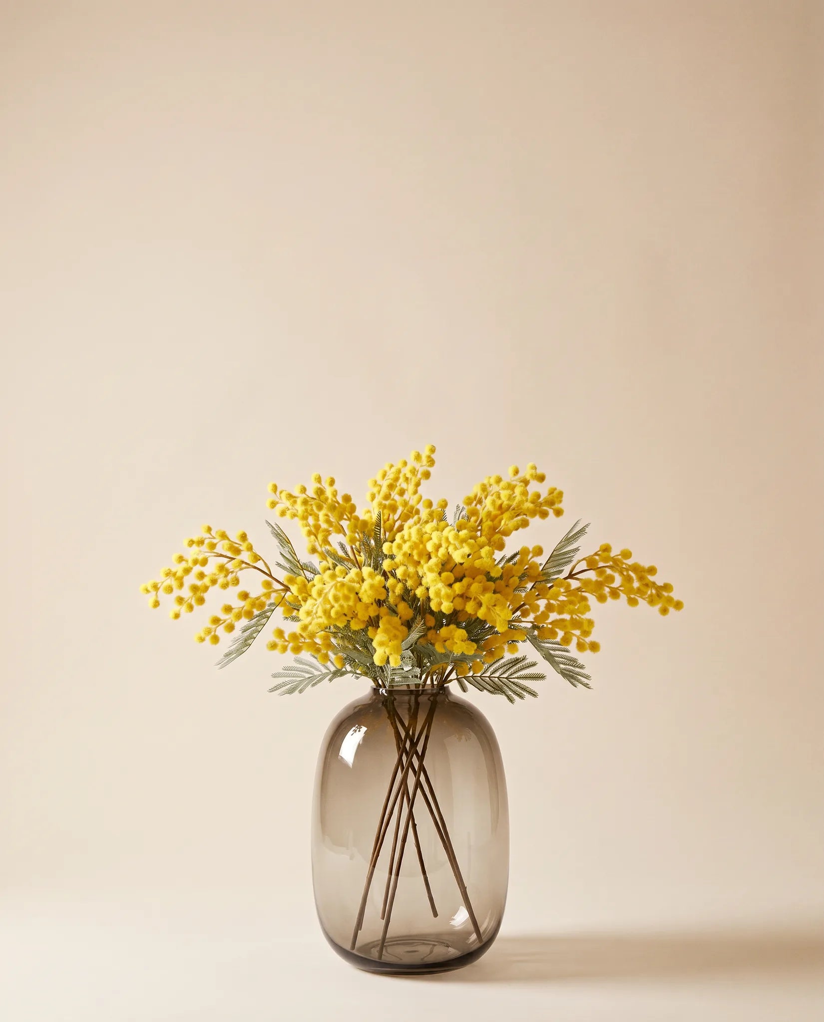 Bouquet artificiel de mimosa jaune dans un vase en verre ambré