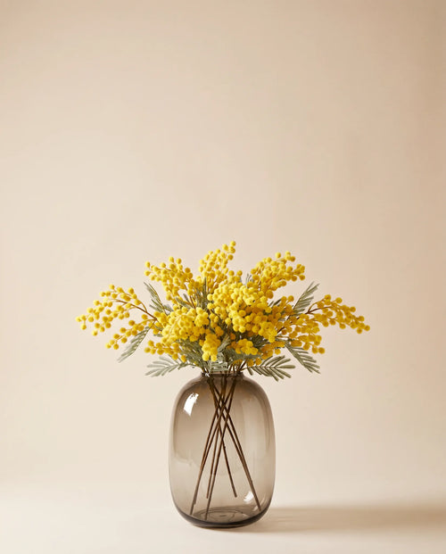 Bouquet artificiel de mimosa jaune dans un vase en verre ambré