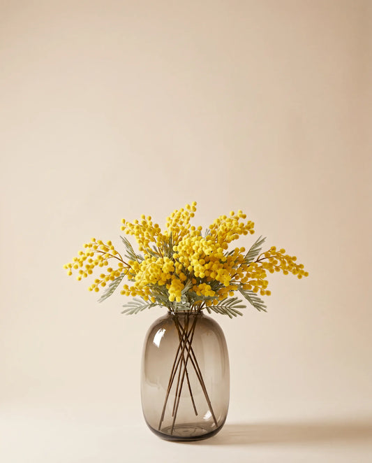 Bouquet artificiel de mimosa jaune dans un vase en verre ambré