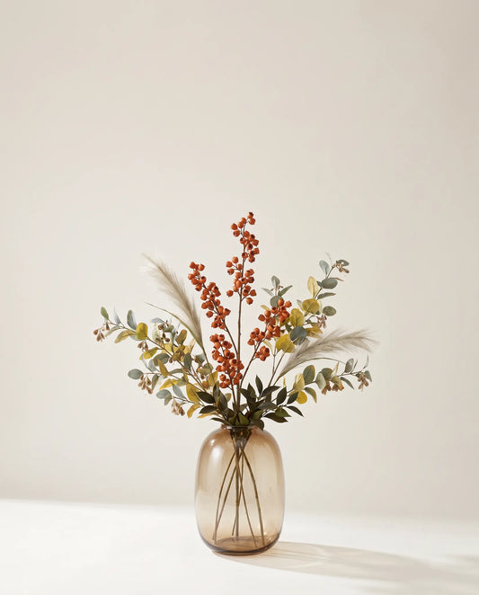 Feuillage artificiel de clochettes, eucalyptus et ruscus rouille et vert dans un vase en verre ambré