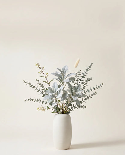 Branches artificielles de symphorine, fleur de cire et cinéraire argent et blanc dans un vase en céramique