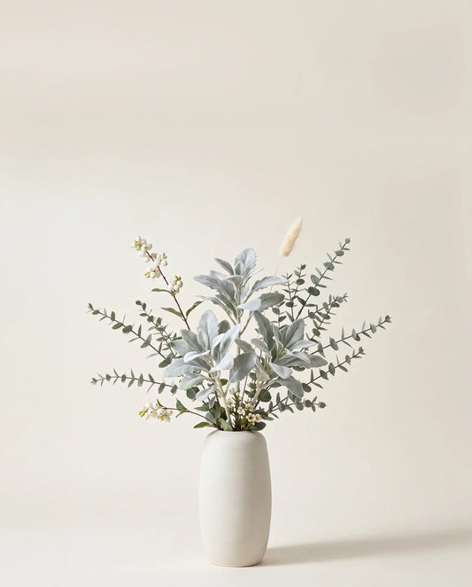 Branches artificielles de symphorine, fleur de cire et cinéraire argent et blanc dans un vase en céramique