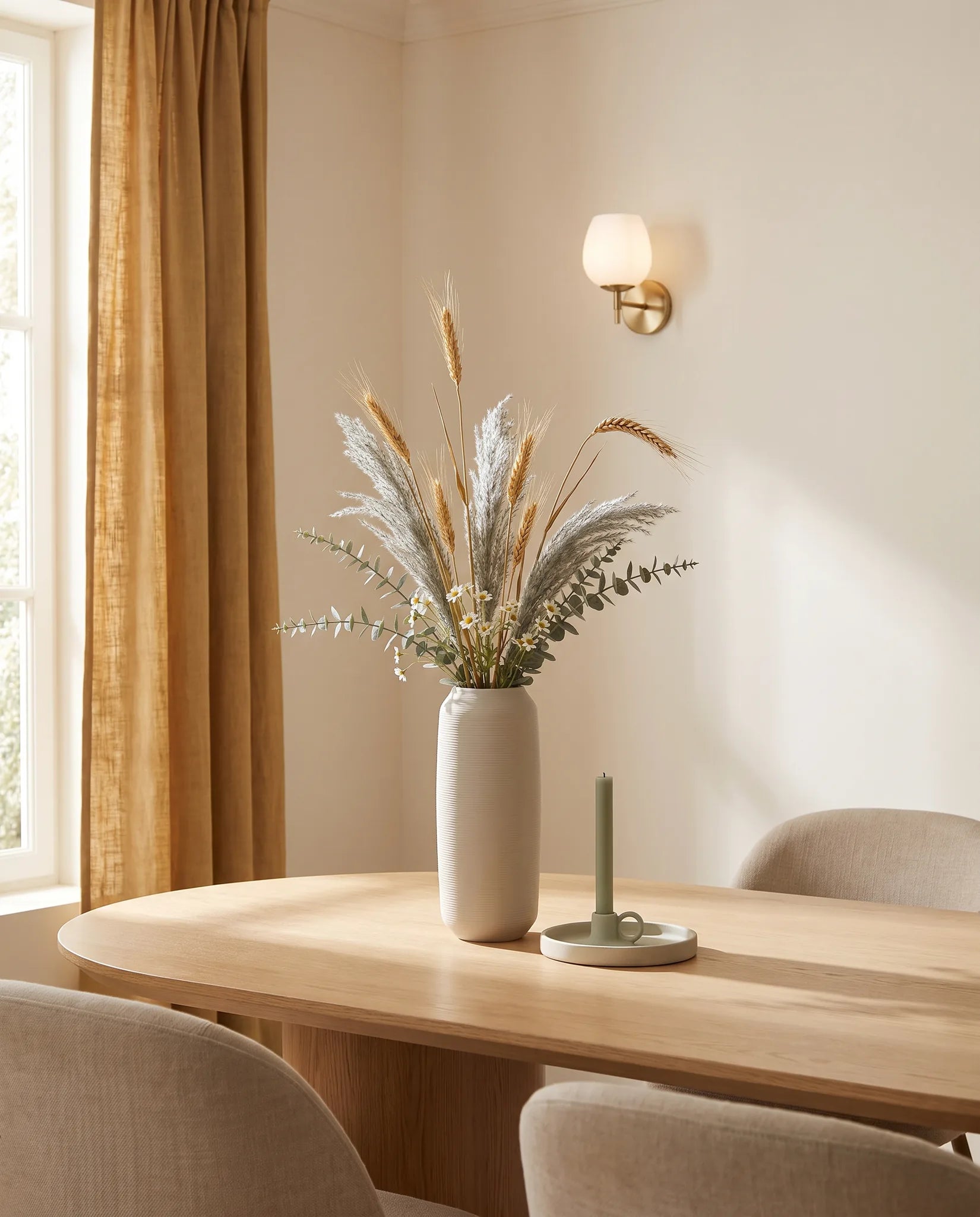 Plante artificielle dorée et vert-gris sur une table ovale en chêne clair dans une salle à manger aux chaises beiges