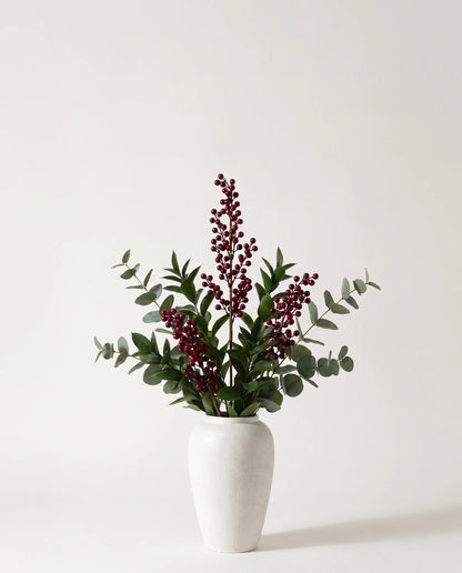 Branches artificielles de baies, ruscus et eucalyptus vert-foncé et bordeaux dans un vase en céramique