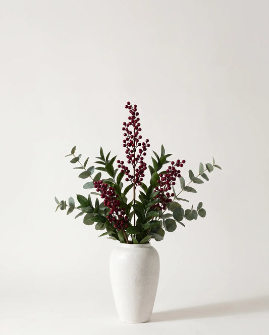 Branches artificielles de baies, ruscus et eucalyptus vert-foncé et bordeaux dans un vase en céramique