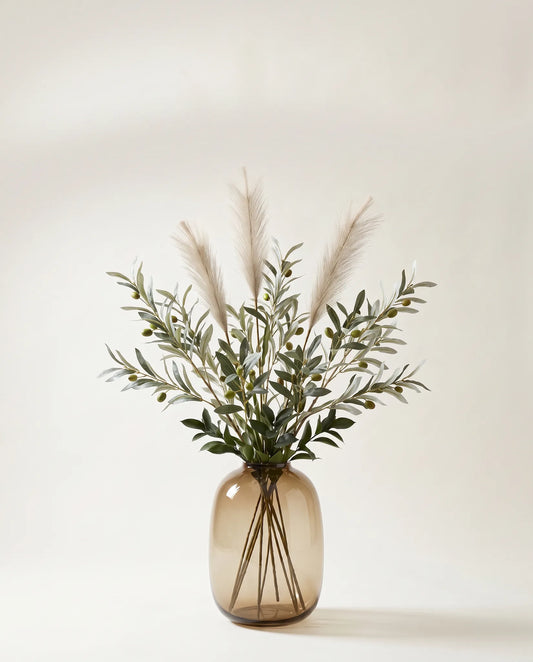 Branches artificielles d'olivier et ruscus vert-olive et crème dans un vase en verre ambré