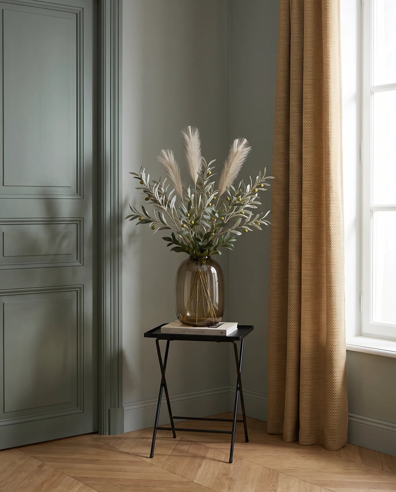 Branches artificielles vert-olive et crème sur une table d'appoint noire dans une entrée au parquet point de Hongrie
