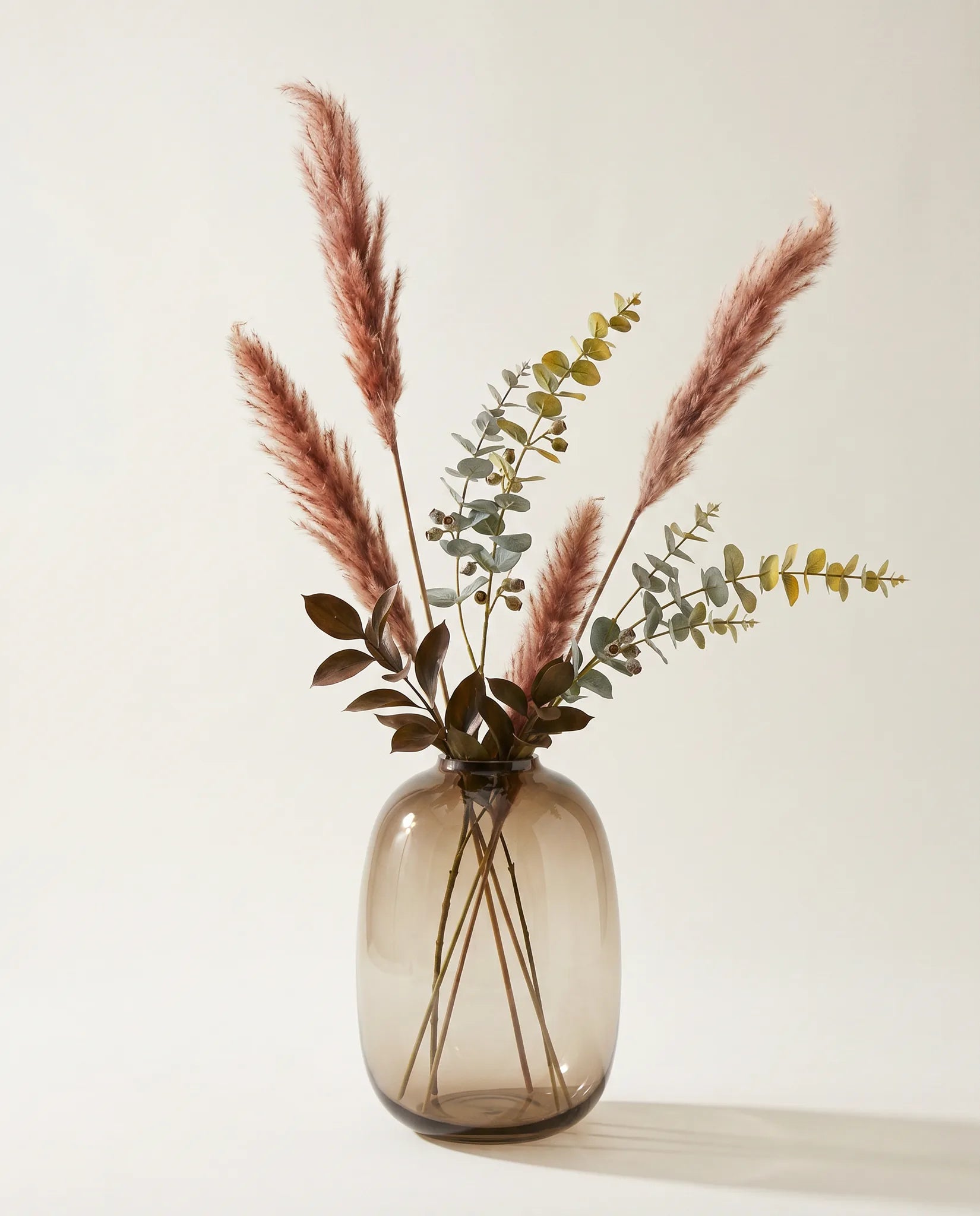 Plante artificielle d'eucalyptus, ruscus et pennisetum rose-rouille et vert en gros plan
