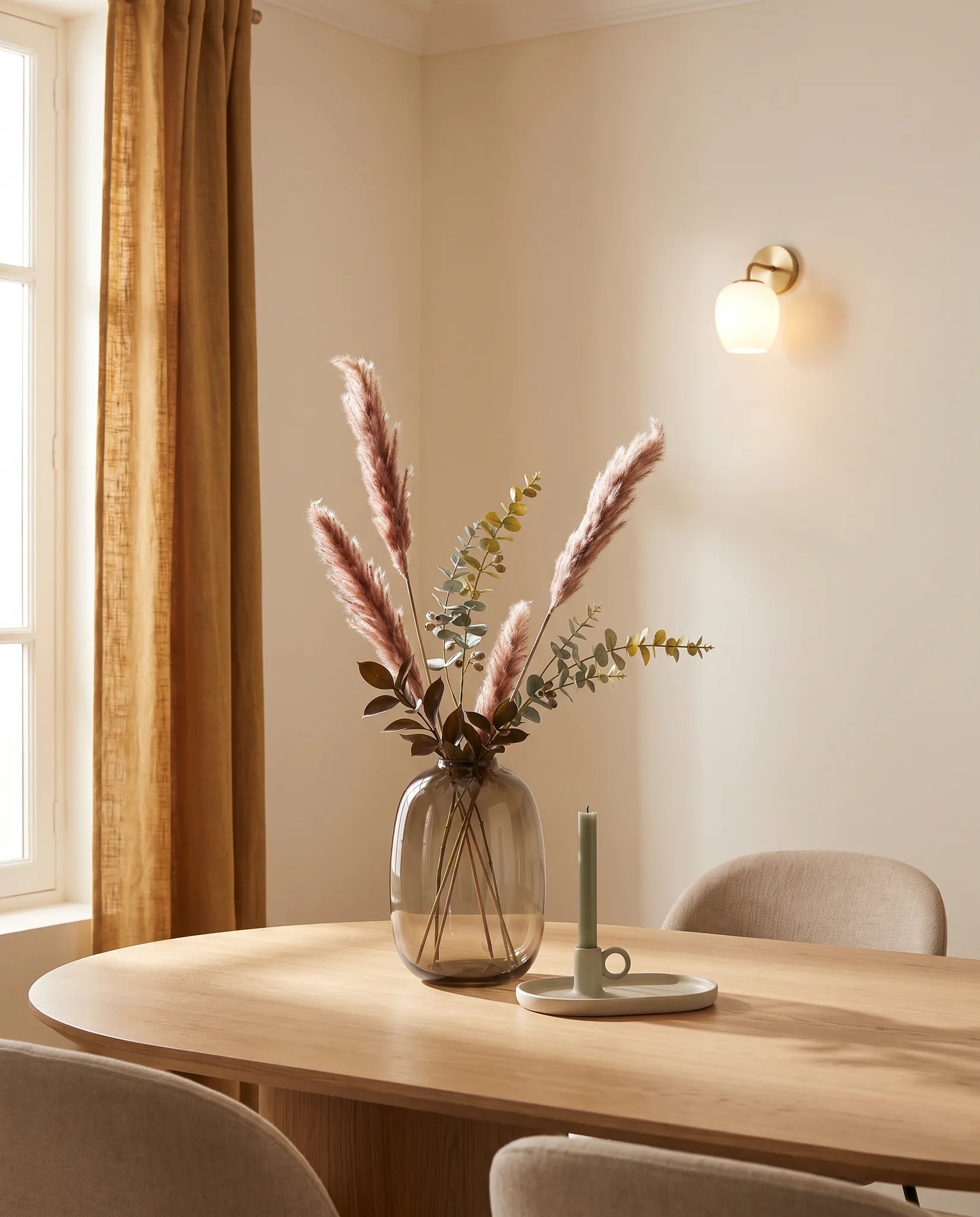 Plante artificielle rose-rouille et verte sur une table ovale en chêne clair dans une salle à manger aux chaises beiges