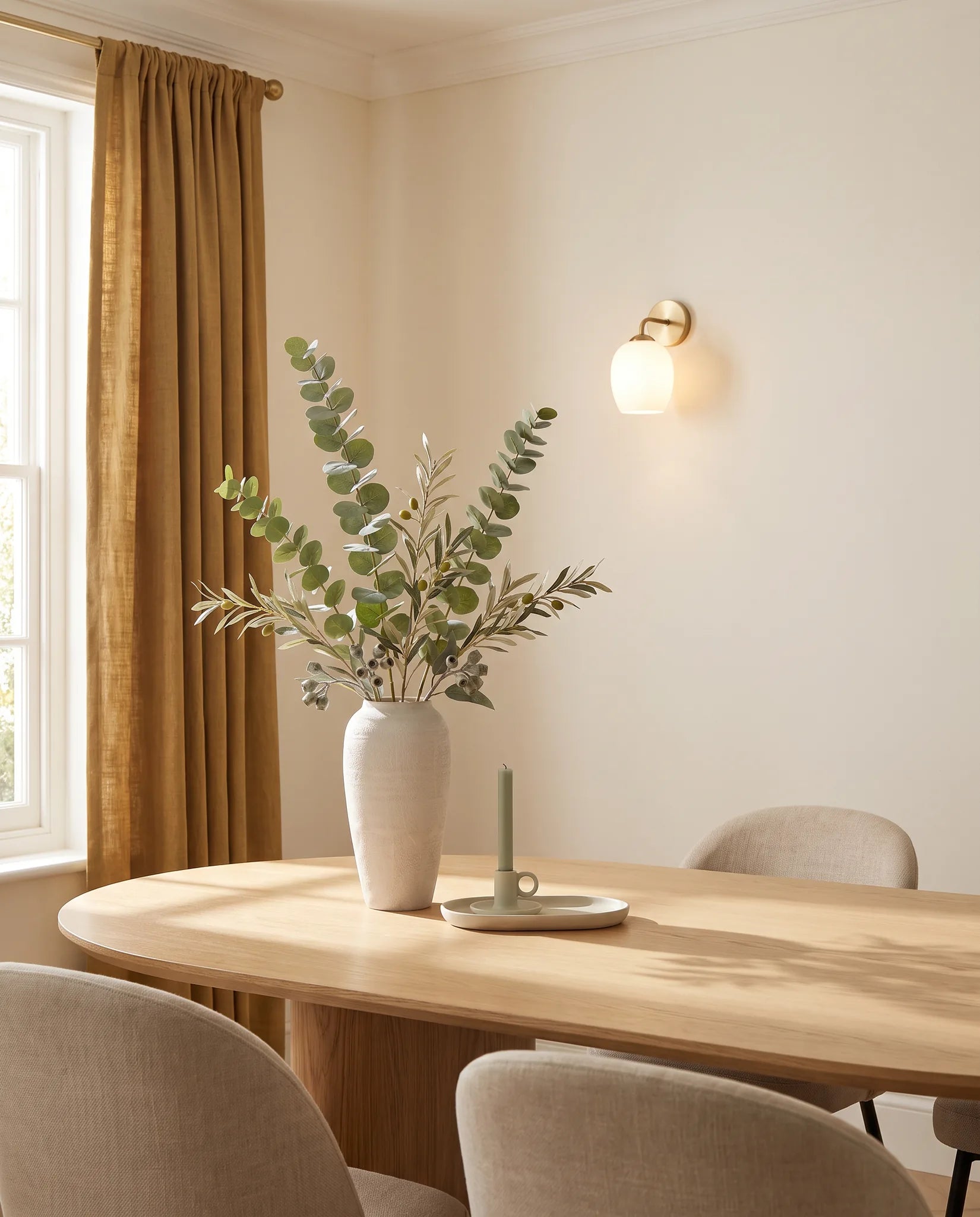 Branches artificielles vertes sur une table ovale en chêne clair dans une salle à manger