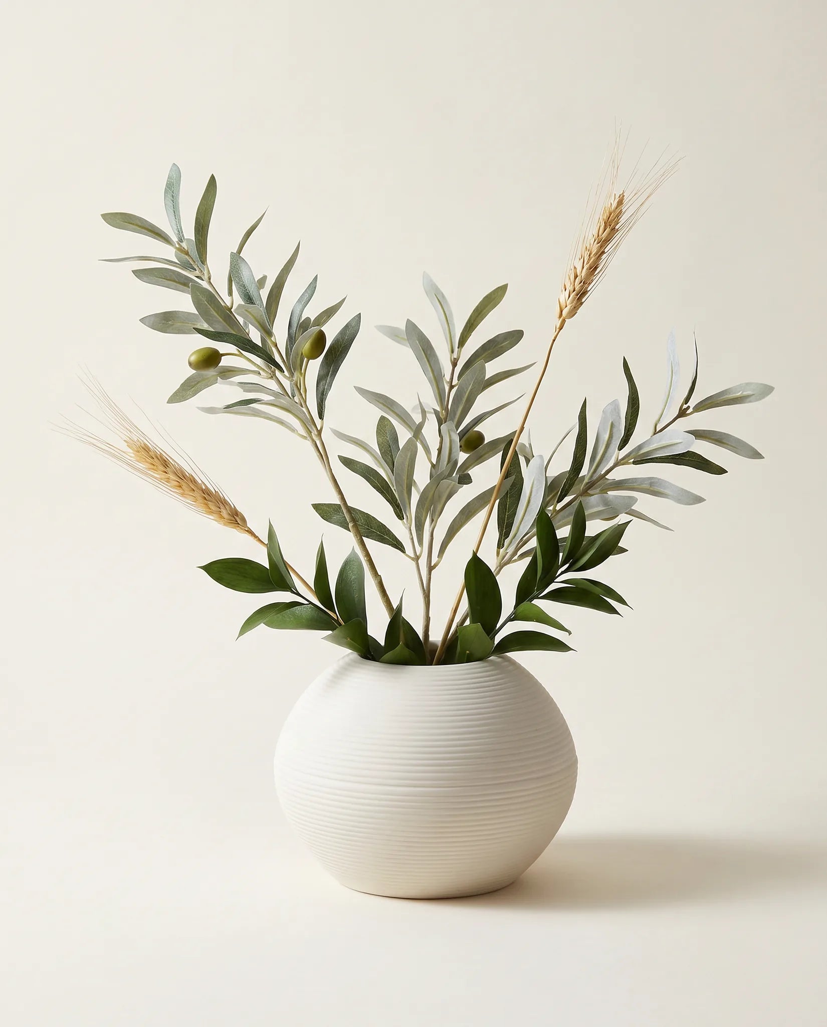 Petite plante artificielle d'olivier, ruscus et blé vert-olive et doré en gros plan