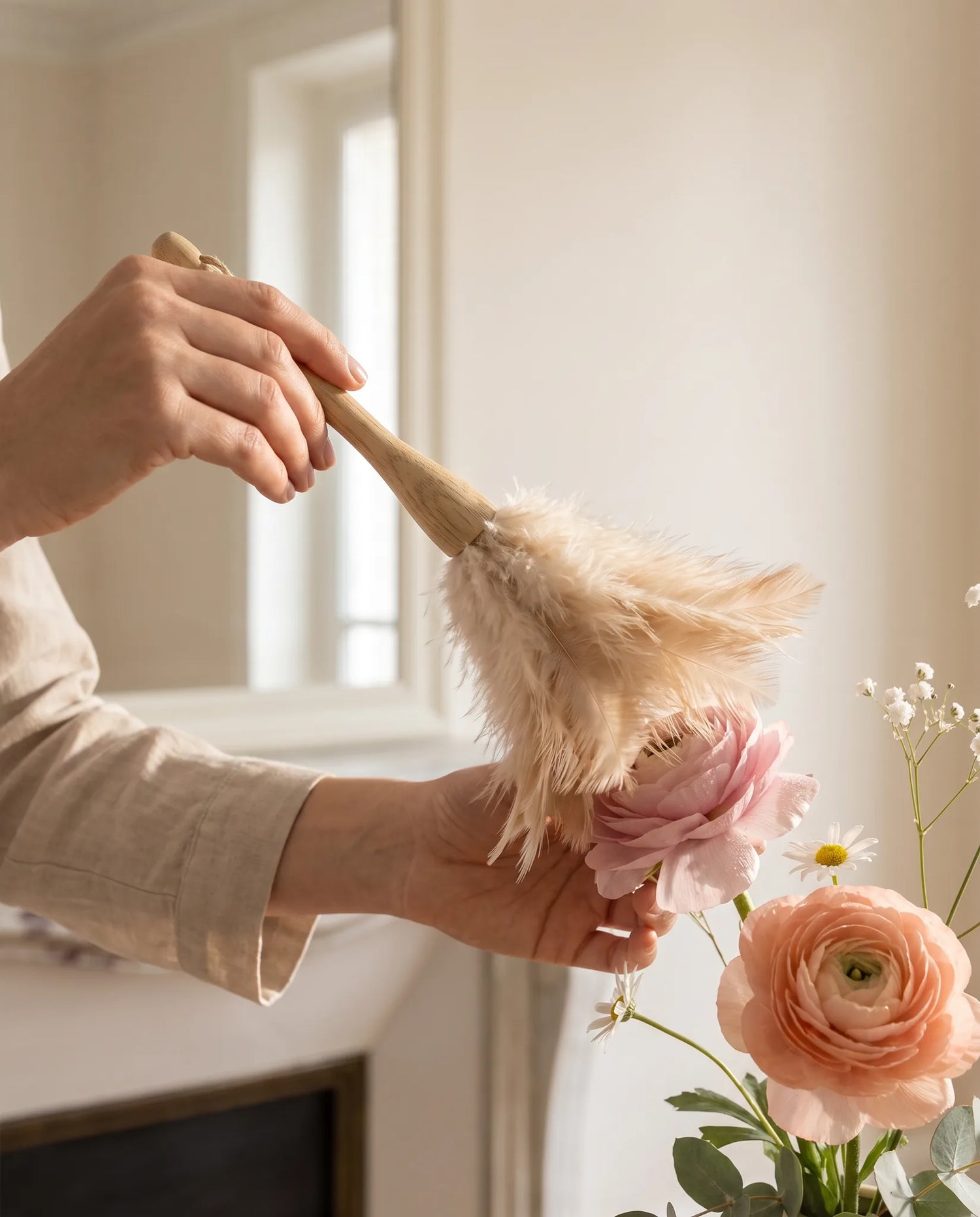 Gros plan d'un plumeau dépoussiérant les pétales d'une fleur artificielle